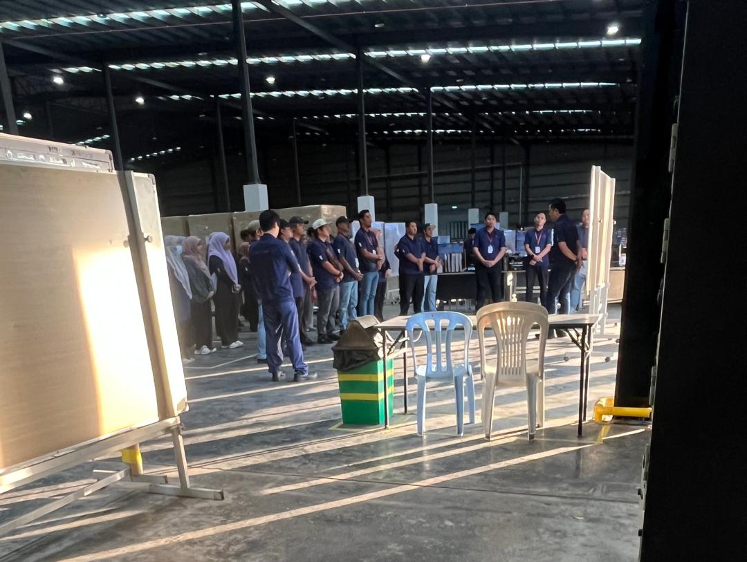 Pekerja kilang dan gudang Millennium Metier menghadiri taklimat keselamatan dan produktiviti di lantai gudang